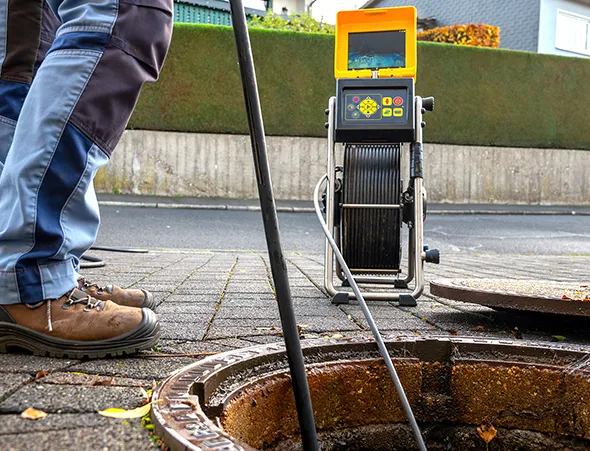 A man is checking the water level in a sewer with a pipe as part of the sewer line cleaning process in Middleton.